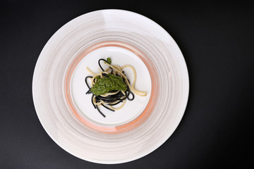 Plate of black and white spaghetti with green souse 