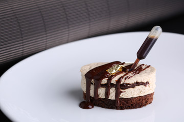 Pigeon's milk cake with cream and chocolate on white plate, dark background