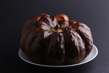 Beef stew with vegetables in pumpkin on white plate, dark background. 