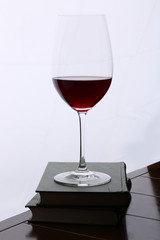Glass of red wine on the books at wooden table against white backdrop