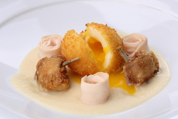 Chicken Balls -  breaded, deep fried balls filled with egg and Chickens legs served bacon, celery puree on white plate. Close up