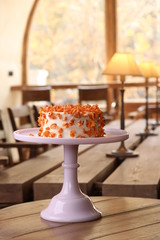 Cake covered in white rolled fondant and decorated with marzipan flowers  on a stand