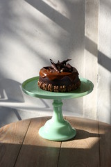 Deliciously divine chocolate cake with cream on pale green shabby chic table.