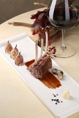 Organic Grilled Lamb Chops with Garlic and sauce on a white plate the background of glass red wine, flowers
