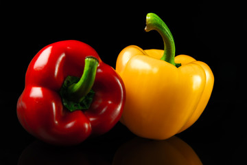 Fresh red and yellow peppers. On a black background