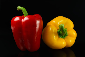 Fresh red and yellow peppers. On a black background