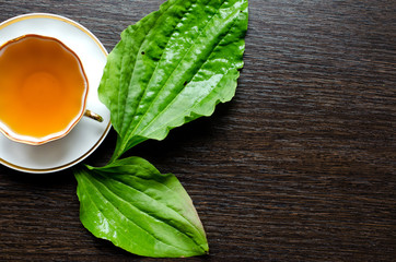 herbal plantain tea in a porcelain Cup on a dark wooden background