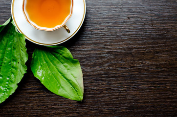 herbal plantain tea in a porcelain Cup on a dark wooden background