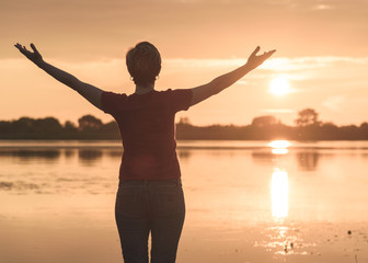 Fototapeta premium young slim woman meditating onbanks of the lake at sunset