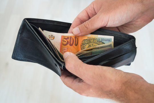Man holding a wallet with dinars inside