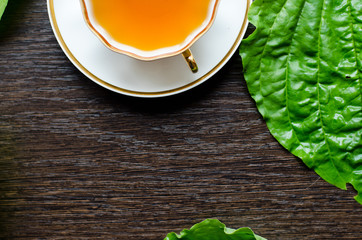 herbal plantain tea in a porcelain Cup on a dark wooden background
