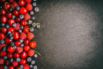 Summer berries (blueberries, raspberries and cherries) on black background. May be used for text.