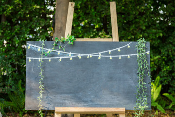 Blank chalkboard with wooden tripod in wedding ceremony with outdoor and garden style