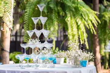 Pyramid of glasses of champagne at outdoor garden in wedding ceremony