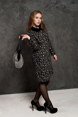 Fashion girl with handbag posing at the background weariing a coat