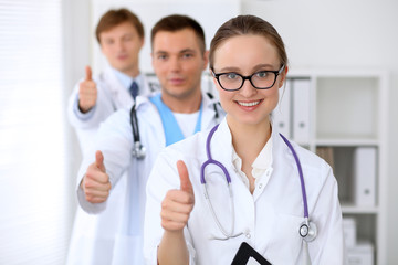 Fototapeta premium Happy doctor woman with medical staff at the hospital. Thumbs up