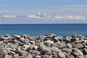 Fototapeta na wymiar Steine am Strand mit Blick auf das offene, blaue Meer - Atlantischer Ozean, La Gomera - Spanien