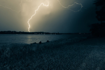Lightning lights up grainy sky over bay.
