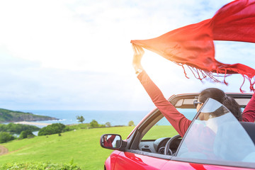 Girl in a red convertible car on  background seascape.