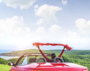 Girl in a red convertible car on  background seascape.