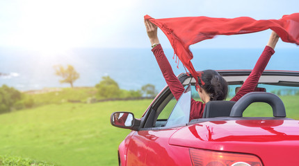 Girl in a red convertible car on  background seascape.