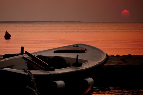 Fishing boat with oars, buoys and rope in sunset on Croatian molo