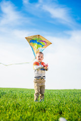 Young boy flies his kite in an open field. Little kid playing with kite on green meadow. Childhood concept.