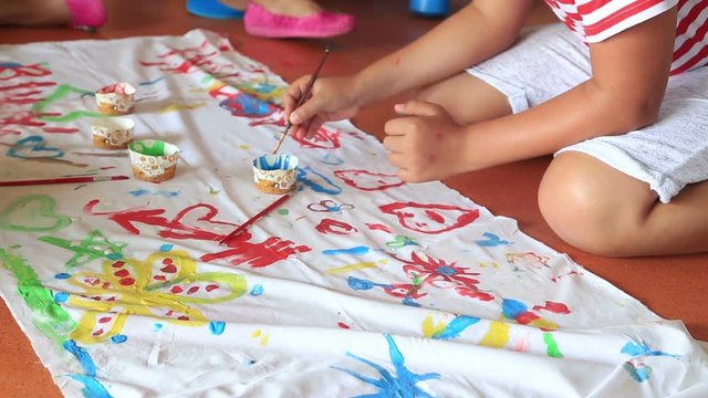 Child painting on a fabric in play room. Child care.