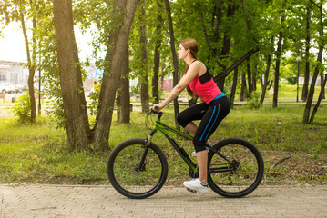 Fototapeta premium Happy girl cyclist riding on a mountain bike outside