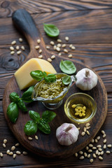 Rustic wooden chopping board with basil pesto and its components