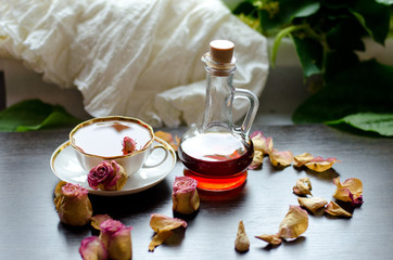 herbal rose tea in a porcelain Cup and Maple syrup on a dark wooden background