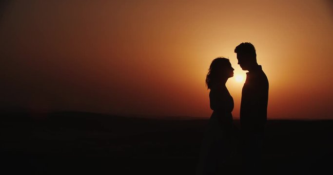 Romantic young couple silhouette. the guy with the girl are lovers, together at sunset, love story, slow motion
