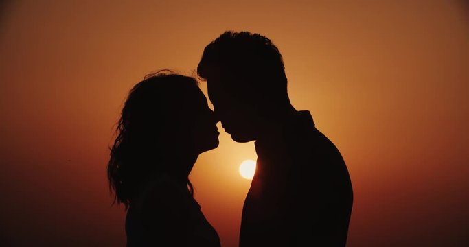 Romantic young couple silhouette. a guy with a girl together are the lovers kiss at sunset, love story, slow motion