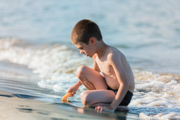 Beautiful boy playing with toys  at the seaside