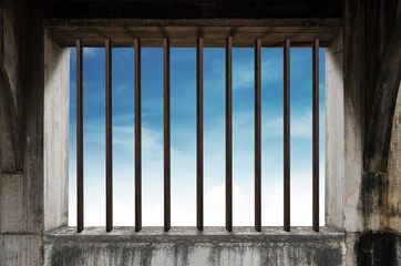 Old window frame with iron bar in jail, and blue sky