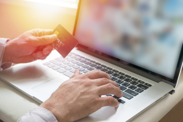 Man holding credit card on laptop for online shopping