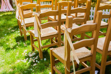 wooden decorated empty chairs on a lawn before wedding ceremony