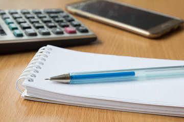 Note paper, blue pen, calculator and mobile phone