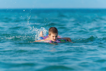 Beautiful boy making splashes in the middle of sea waves swimmin