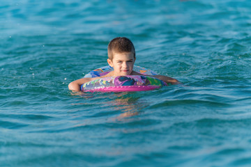 Fototapeta na wymiar Beautiful boy making splashes in the middle of sea waves swimmin