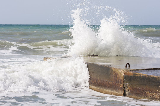 Sea waves breaking on the concrete pier