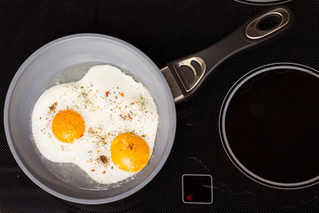 Frying pan with cooked two eggs and spices