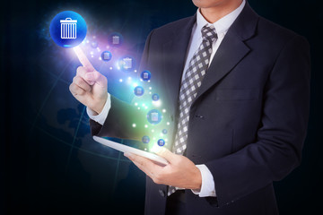 Businessman holding tablet with pressing bin trashcan icon button. internet and networking concept