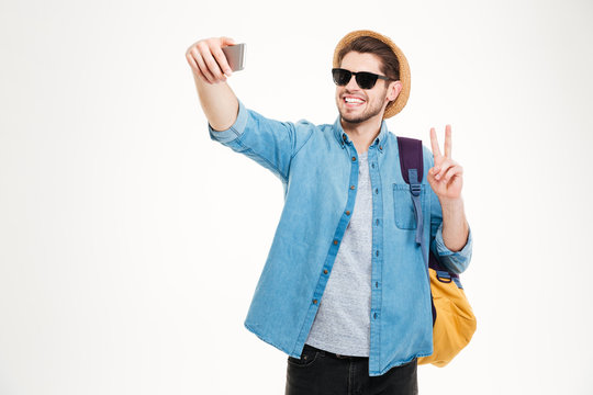 Happy man with backpack making selfie and showing peace sign