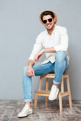 Cheerful young man in sunglasses sitting and smiling