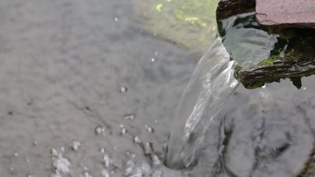 klares Wasser rinnt aus einem rostigen Rohr