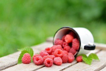 Fresh red raspberries on wooden table on blurred natural background