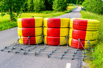 Roadblock made of yellow and red painted car tires. Bridge behind is getting new railings for improved safety.