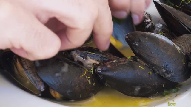 An ultra closeup POV shot of foodie sampling fresh mussels with butter sauce
