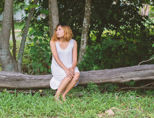 Young beautiful woman sitting at wood bench and so lonely.